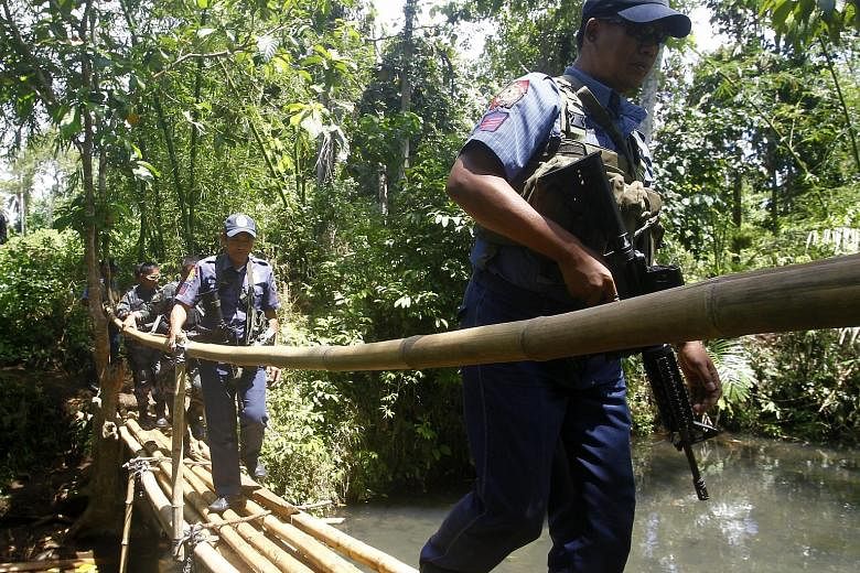 Filipino policemen crossing a wooden bridge yesterday during a military offensive on the outskirts of Jolo. Abu Sayyaf militants are holding more than 20 foreigners captive.