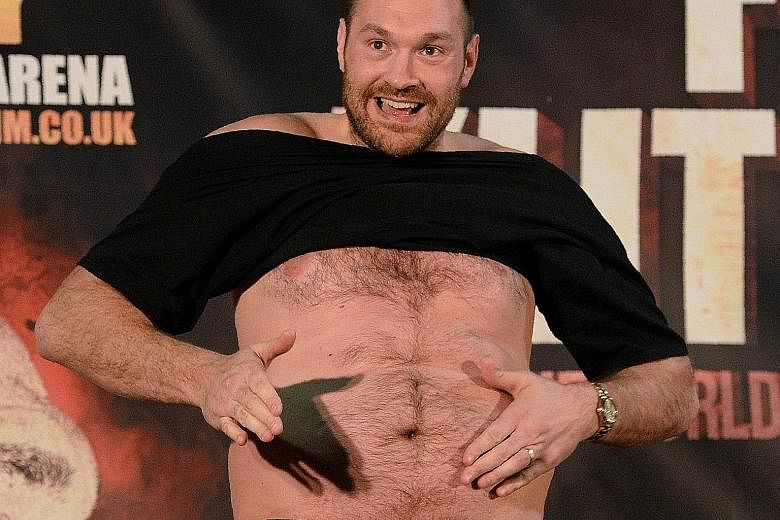British world heavyweight champion Tyson Fury shows off his flab at a press conference in Manchester on Wednesday while taunting Wladimir Klitschko of Ukraine before their world title re-match in July.