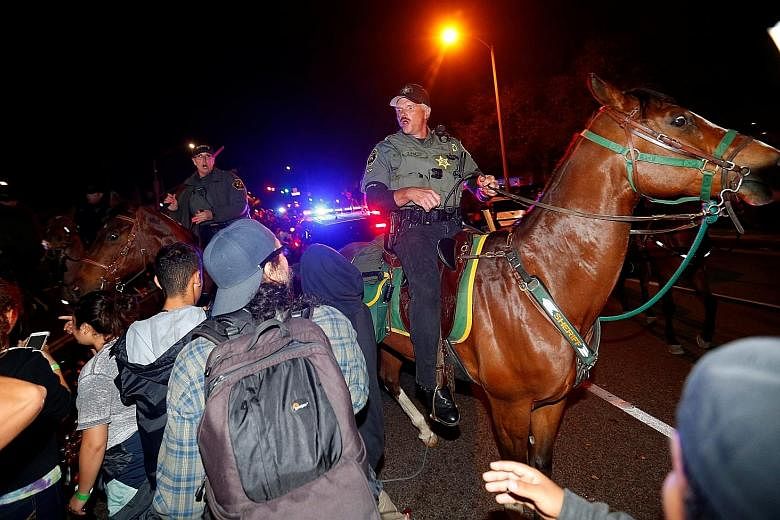 Sheriffs and police officers on horseback breaking up a group of demonstrators outside Republican presidential candidate Donald Trump's campaign rally in Costa Mesa, California, on Thursday. Observers see a Trump nomination as inevitable.