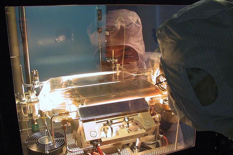 A DenseLight engineer processing wafers at its Changi Industrial Park facility. The firm's products are used in communications, healthcare, navigation, and oil and gas exploration and production.