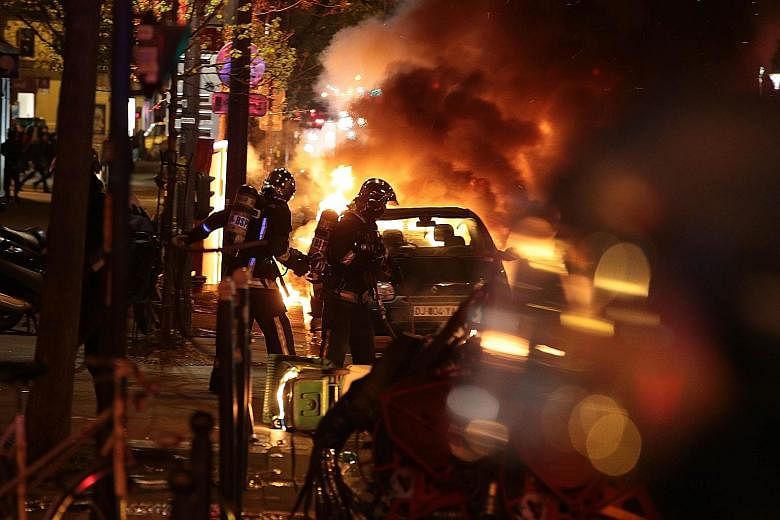Firefighters putting out the flames on a burning car early yesterday as French security officers cleared the Place de la Republique during a protest by the Nuit Debout, or "Up All Night" movement.