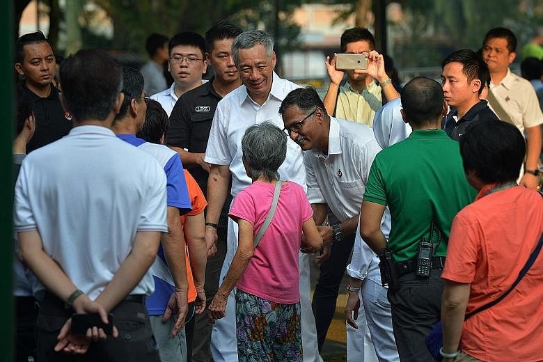 Mr Murali greeting an elderly resident at Bukit Batok Central Park yesterday as PM Lee looks on. Mr Lee said Mr Murali's commitment is beyond doubt, and he would be backed by a town council with a good track record.
