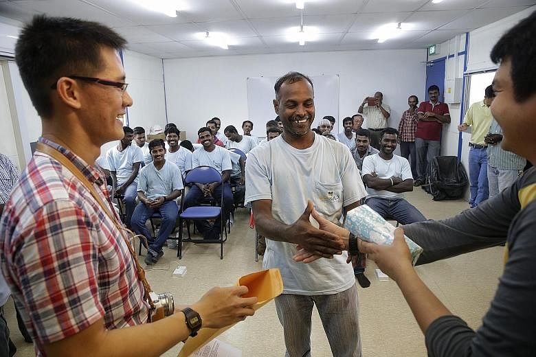 Volunteers working with Project Chulia Street, which aims to provide good nutrition, dental care and skills classes for migrant workers here, organised games (above) for all to take part in; Right: Mr Saminathan Muruganandan (centre), 40, receives hi