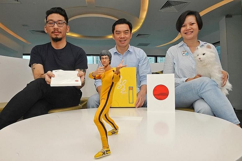 Creative directors of graphic design studio Couple Kelvin Lok (left) and Zann Wan (right) and Lien Foundation's CEO Lee Poh Wah (centre), with some of the quirky annual reports that the foundation has published over the years. Mr Lee is holding the 2
