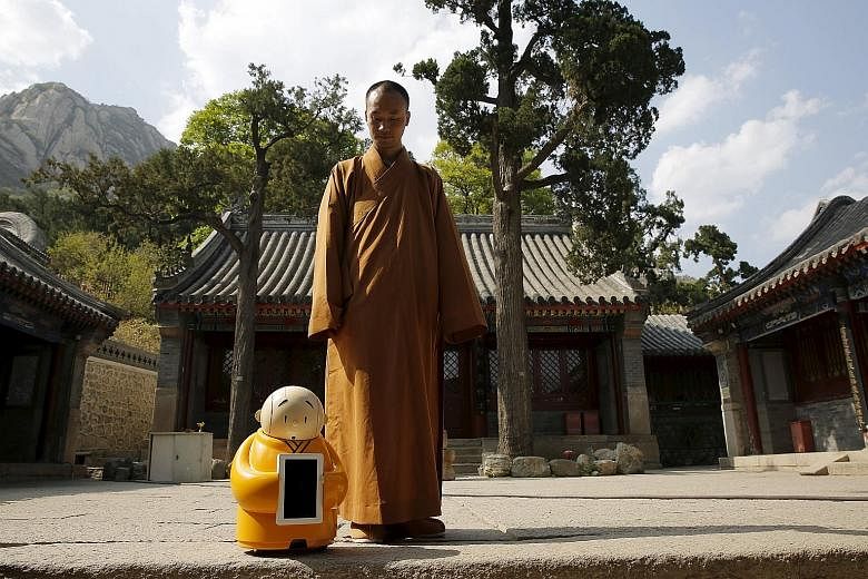 Master Xian Fan with Xian'er, a 60cm-tall, advice- dispensing robot monk, in Longquan Temple on the outskirts of Beijing.