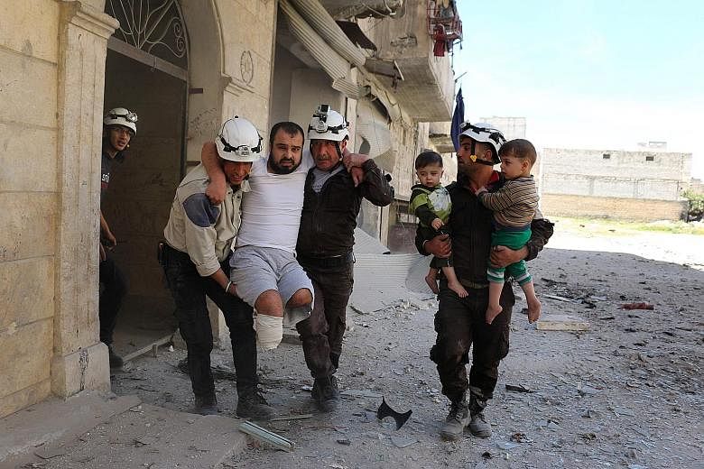Syrian civil defence volunteers evacuating a man and children from a residential building following a reported air strike on the rebel-held eastern neighbourhood of Bab al-Nayrab in Aleppo last Friday. A new temporary truce was brokered by the US and