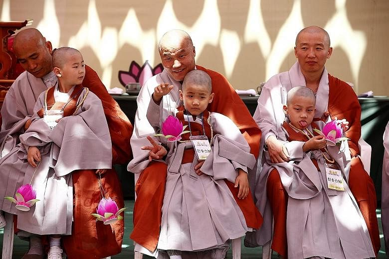 Boy monks sitting with older Buddhist monks during the "Children becoming Buddhist monks" ceremony at the Jogyesa temple, the chief temple of the Jogye Order of Korean Buddhism, in Seoul, South Korea, yesterday. The children will stay at the temple f