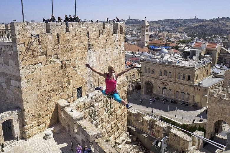 Ms Heather Larsen from Golden, Colorado, performing a split while walking a 35m highline strung between two towers - the tower on the left was built by King Herod some 2,000 years ago - in the Tower of David citadel complex overlooking the Old City o