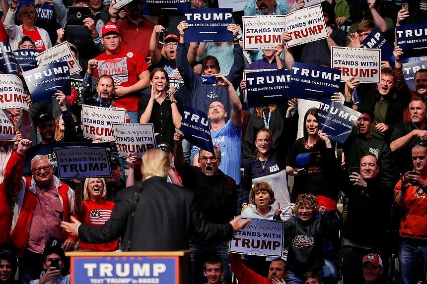 Mr Trump speaking to supporters during a campaign rally at the Allen County War Memorial Coliseum in Fort Wayne, Indiana, on Sunday. Protesters with an inflatable effigy of Republican presidential candidate Donald Trump holding a Ku Klux Klan hood du