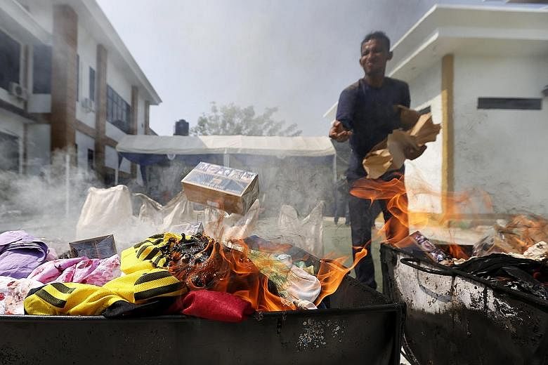 A Customs officer burning illegal products at the Banda Aceh Customs headquarters in Indonesia yesterday. Indonesia has a big market for illegal goods coming from China and other Asian countries.