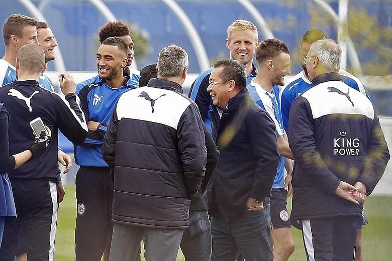 Leicester City's Thai chairman Vichai Srivaddhanaprabha (in dark jacket) celebrating the club's title win with coaching staff and players during a training session yesterday. The billionaire has left a distinctly Thai mark on the team.