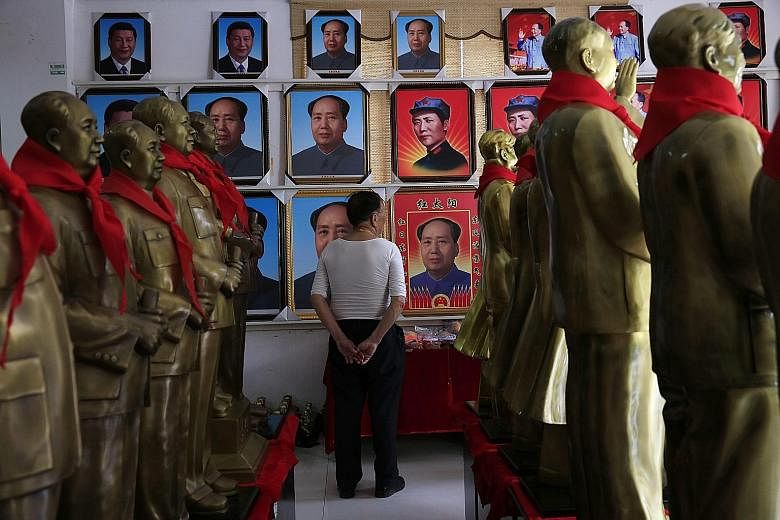 A visitor gazing at portraits and statues of former Chinese leader Mao Zedong at a souvenir store in Shaoshan in the hilly region of central Hunan province. Shaoshan was Mao's home town, and thousands visit it every day to pay homage to the "Great He