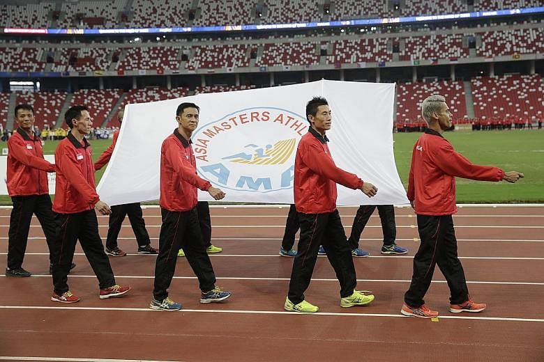 Singapore athletes during the march-past at the National Stadium to music from the Singapore Police Force’s band at the opening ceremony of the Asia Masters Athletics Championships yesterday.