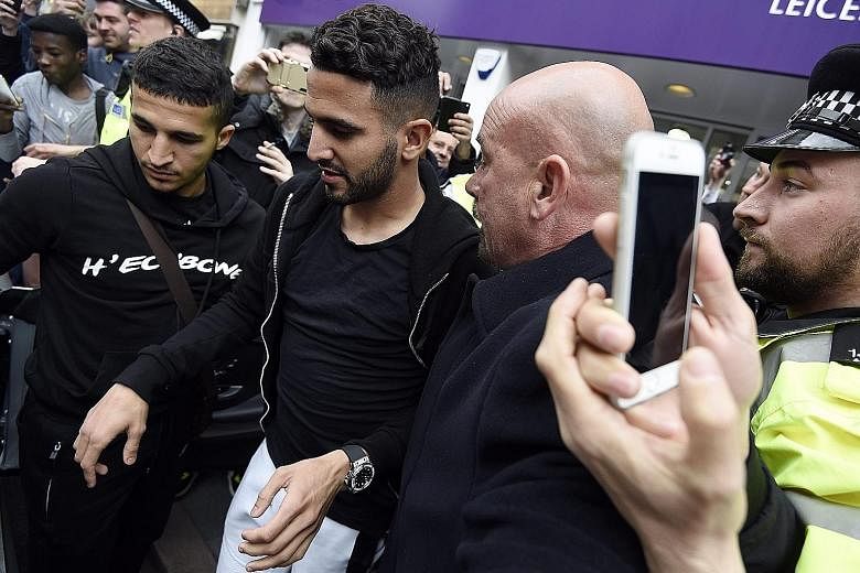 Leicester City's Riyad Mahrez is helped to a car after leaving a restaurant where he and his team-mates were celebrating their league win. The Algerian has become much sought after after his consistently swashbuckling displays were instrumental in he