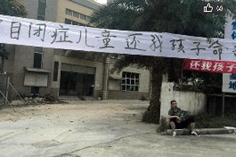 Jia Jia's father (left) sitting under a banner that reads "I want my son back" outside the rehabilitation centre in Guangdong. The little boy (above) was autistic.
