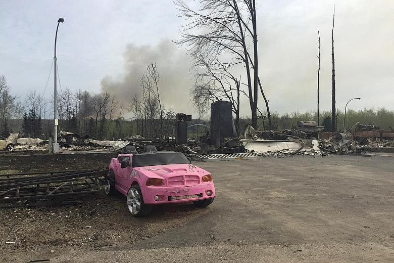 (Clockwise from right) A pink car sits forlorn among the ruins after wildfires tore through Fort McMurray this week; a wasteland of destroyed homes; evacuees taking stock of their situation.