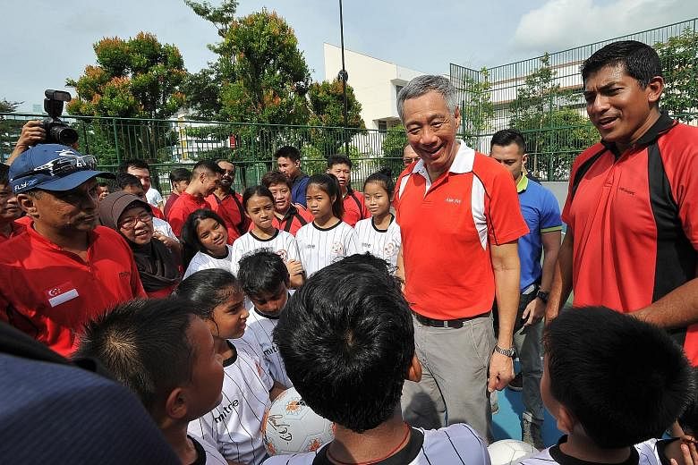 PM Lee mingling with children at the street soccer court of the revamped Ci Yuan Sports Park yesterday. Accompanied by Ang Mo Kio GRC MP Darryl David (right), he joined more than a thousand residents in doing workouts, watching street football, and t