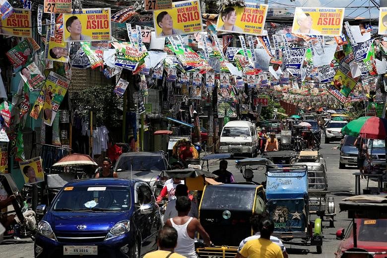 Presidential candidates' election posters hanging above a main street in Pritil, Tondo city, in Metro Manila yesterday. Opinion polls show that Mr Duterte is ahead by 11 percentage points over his closest rival, Senator Poe. The results of today's el