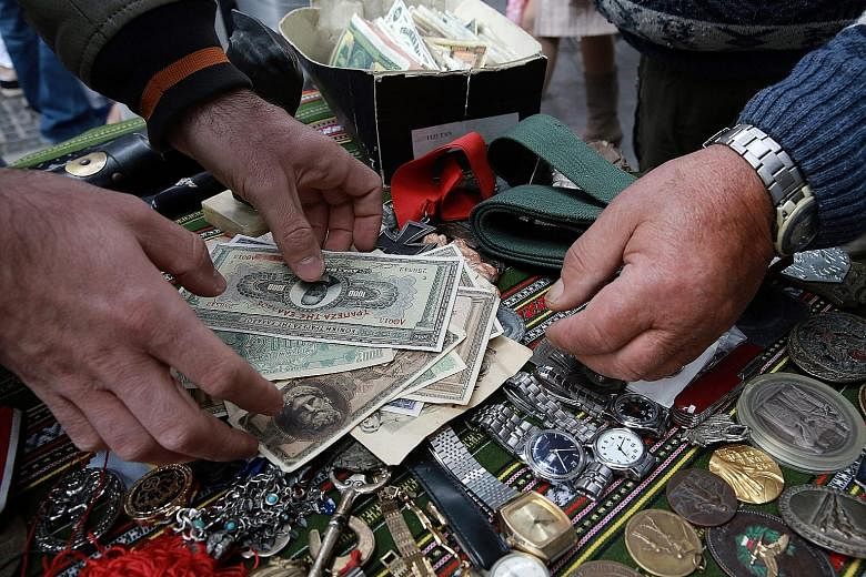 A street vendor selling old Greek banknotes, among other things, in central Athens. The country faces default if it fails to receive loans to cover €3.5 billion (S$5.4 billion) in maturing debt in July.