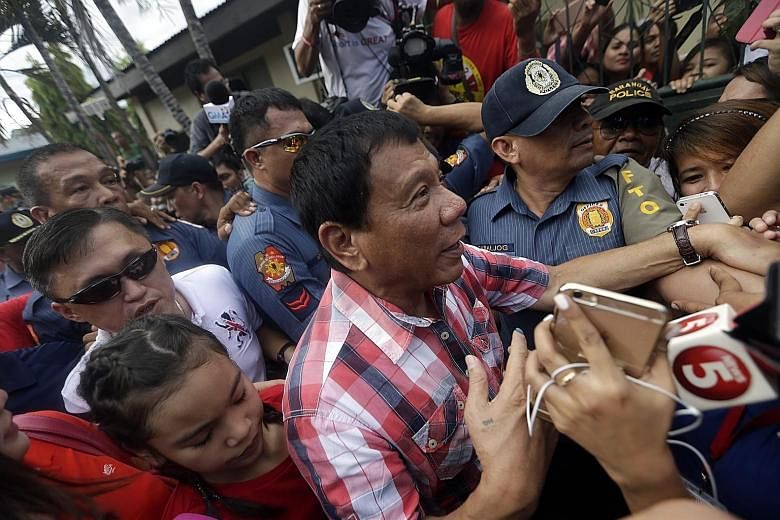 Supporters surrounding Mr Duterte after he cast his vote yesterday in Davao city. He is on track to become the next president of the Philippines, with unofficial results showing that he has an insurmountable lead over his rivals.