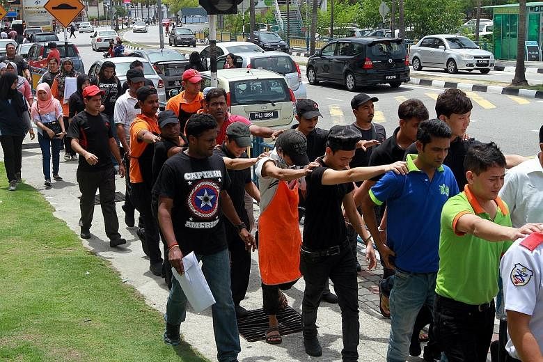 Foreign workers in Malaysia without valid travel documents or work permits being led away by enforcement officers during an Immigration Department raid at a mall in Penang this month. There are some two million illegal foreign workers in the country.