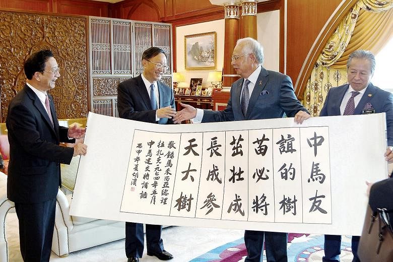 Malaysian Prime Minister Najib Razak and China's State Councillor Yang Jiechi shaking hands after the presentation of a calligraphy scroll to the Malaysian leader yesterday. Also present at the event were Malaysian Foreign Minister Anifah Aman (right