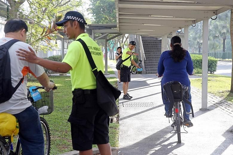 Active Mobility Enforcement Team officers keeping an eye on cyclists and people using personal mobility devices in Woodlands Avenue 7 yesterday morning. They handed out brochures with safety tips for cyclists and also issued advisory notices to those