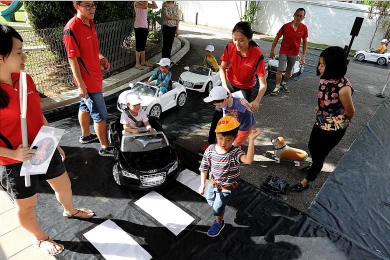 Pre-schoolers from Pat's Schoolhouse getting a feel of the road in Audi R8 mini-electric cars and as pedestrians crossing the street while being supervised by staff from the Singapore Toy Club yesterday. They were in an interactive road safety progra