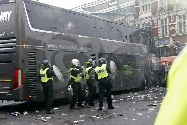 As bottles and other debris litter the street, riot police armed with shields take up their positions beside the Manchester United team bus, which was damaged in the pre-game attack on Tuesday.