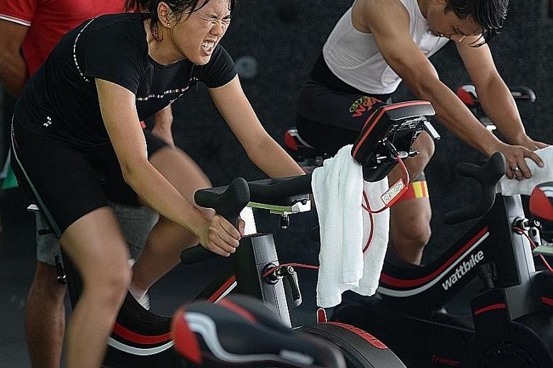 Triathlete Winona Howe (in black) and former S-League player Hilmi Azman were put through their paces on a stationary watt bike yesterday. The two are among 145 cyclists hoping to get a place in the national training squad.