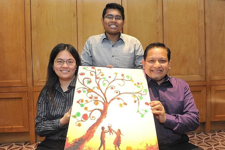 Mr Mohamed Fazly (centre), assistant director, community policy, at Singapore Prison Service, with Ms Edlyn Tan and Mr Mohamed Fawzi Ali, both volunteers with the Yellow Ribbon Community Project. The painting they are holding is the work of former of