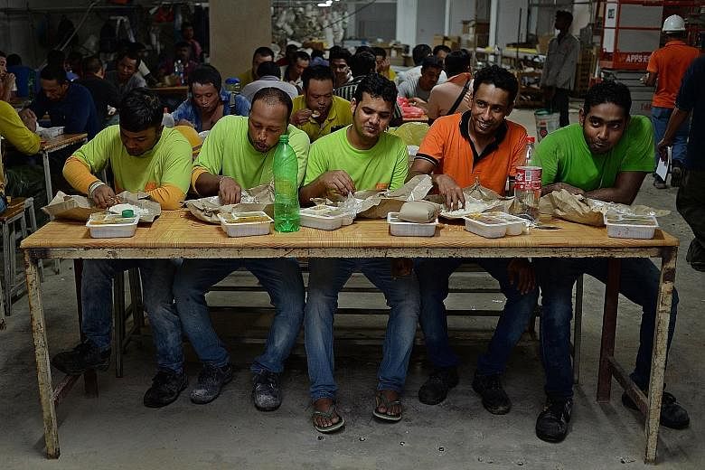 Workers from Unison Construction having their lunch at their worksite on Wednesday. Unison is one of three firms participating in a pilot programme run by social enterprise 45Rice that ensures hot meals are delivered to foreign workers thrice a day. 