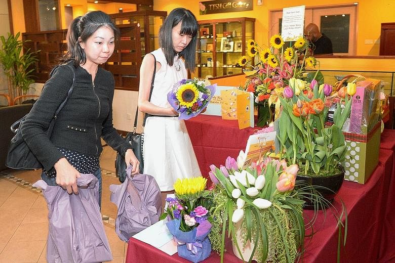 Tampines residents Kathy Goh (left), 31, and Janessa Thng, 30, leaving flowers at Tan Tock Seng Hospital, where Mr Heng remains in the intensive care unit. They were among many who visited the hospital yesterday to place get-well cards, flowers and g