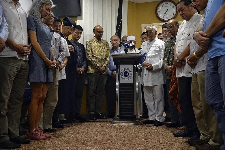 Deputy Prime Minister Tharman Shanmugaratnam, Parliamentary Secretary Baey Yam Keng, religious leaders from the Inter-Religious Organisation (IRO) and guests observing a minute of prayer for Mr Heng at the IRO office yesterday.