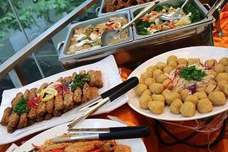 A birthday-party buffet spread in Pasir Ris provided by Kuisine Catering on Feb 13 (top). The Kuisine Catering premises were shuttered and delivery vans were seen nearby when ST visited on Feb 19.
