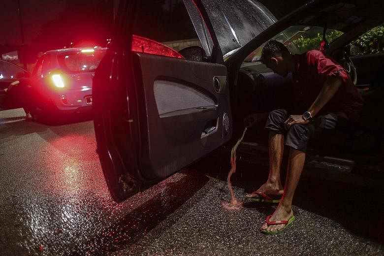 A man scoops water from his car after flash floods hit Kuala Lumpur, causing severe traffic jams and even trapping some people in their vehicles. Officials say they are looking into ways to mitigate the flooding.