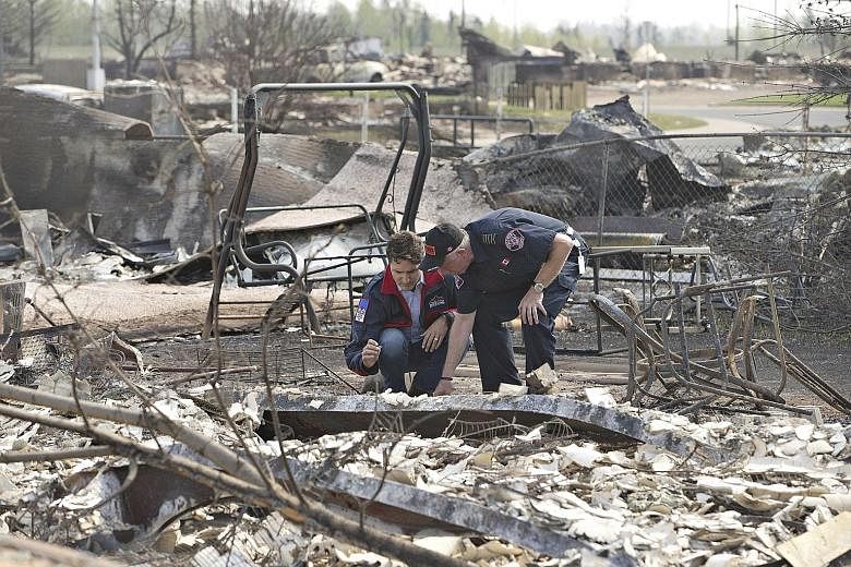 Canadian Prime Minister Justin Trudeau (left) and Fort McMurray fire chief Darby Allen visiting a neighbourhood that was devastated by a wildfire that forced the evacuation of the city of Fort McMurray, in Alberta, Canada, on Friday. Known as "the be