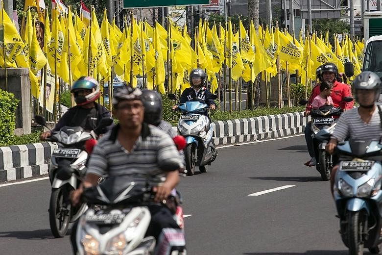 Motorcyclists riding past large flags of the Golkar party, which officially started its national congress in Bali yesterday. The meeting of Indonesia's second- biggest party in Parliament was opened by President Joko Widodo. Eight leaders are contest