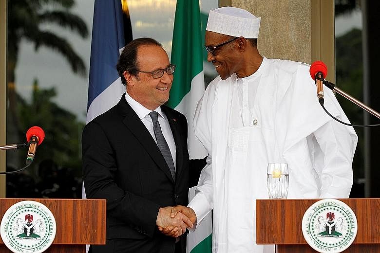 French President Hollande (left) with Nigerian President Buhari at a joint news conference in Abuja, Nigeria, yesterday. They held talks at the presidential villa before regional leaders met to discuss the terrorist conflict.
