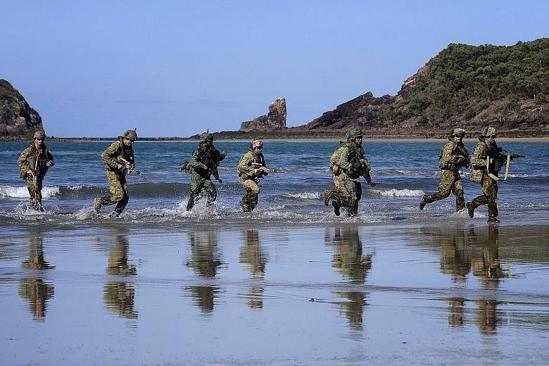 (Above) Troops from the Singapore Armed Forces and the Australian Defence Force during a preview of Exercise Trident at Freshwater Bay in Rockhampton, Queensland. (Below) Another scene from Exercise Trident.