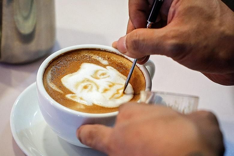 Filipino graphic artist and barista Zach Yonzon draws the face of Philippine President-elect Rodrigo Duterte on a cafe latte called Latte Duterte inside his cafe and cake studio in Quezon city, north-east of Manila.