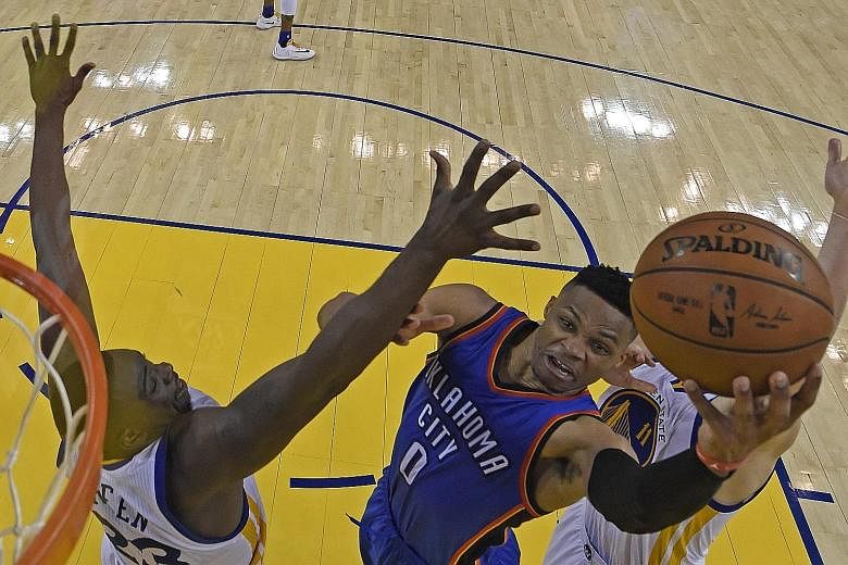 Thunder guard Russell Westbrook (centre) drives to the basket as Warriors forward Draymond Green attempts to defend.