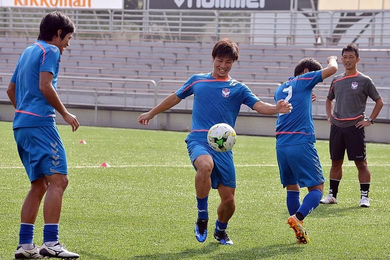 Albirex Niigata forward Atsushi Kawata (centre) controlling the ball in training at Jurong East Stadium as his coach Naoki Naruo (right) looks on. The league's leading striker aims to win the Golden Boot and also fire his side to their first S-League