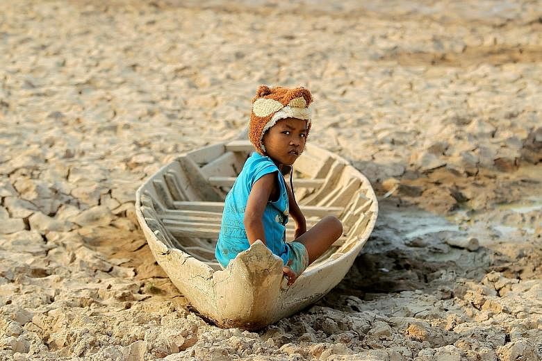 A girl sitting in a boat on a dried-up pond in the drought-hit Kandal province in Cambodia. Cambodia is grappling with soaring temperatures and its worst drought in decades. Eighteen of the country's 25 provinces are suffering from water shortage as 