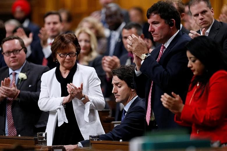 Members of the Liberal caucus applauding Mr Trudeau (seated) after he delivered his apology on Thursday. The Canadian Prime Minister said he was only human and promised that there would be no repeat of his actions.