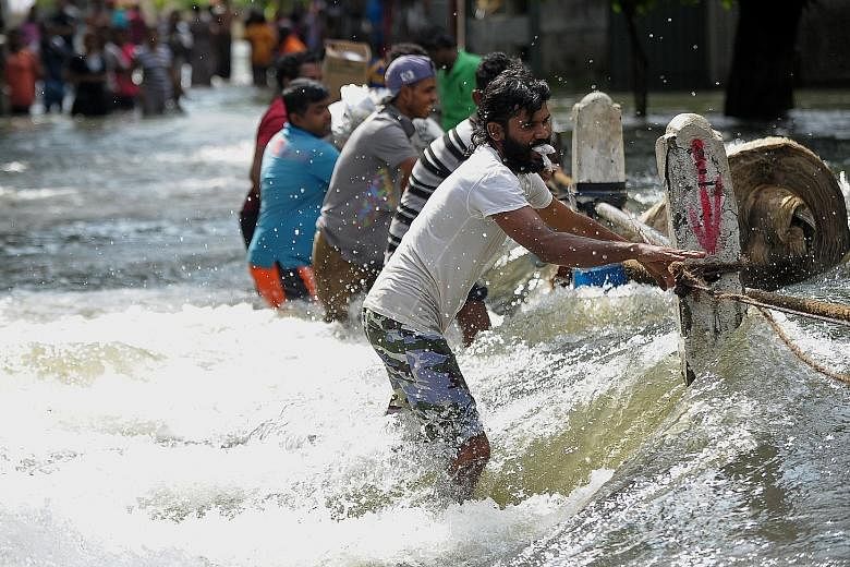 (Above) Volunteers evacuating residents in Kaduwela suburb in Colombo. (Left) An official battling the floodwaters to deliver cooked meals to victims marooned in a building in Colombo. Sri Lankans struggling against a torrent in the flooded outskirts