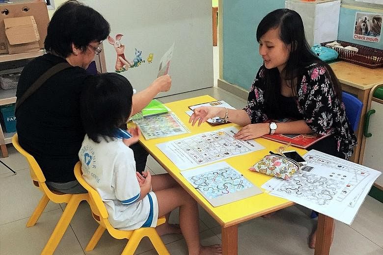 A volunteer helping a parent and child at a Transition to P1 playshop organised under the Circle of Care scheme, which has led to higher rates of school attendance and gains in learning for at-risk children at the two centres in Leng Kee and Admiralt