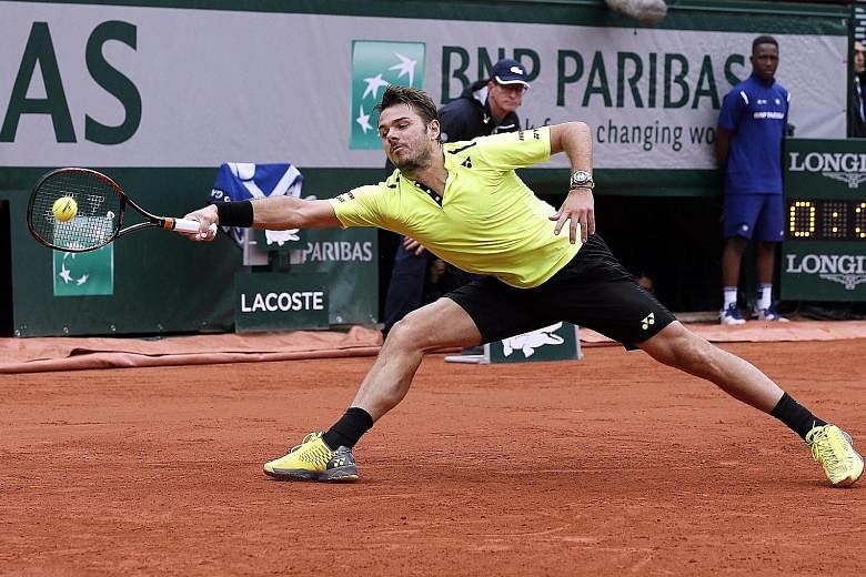 Defending champion Stan Wawrinka of Switzerland slides for a forehand during his five-set win against Lukas Rosol of the Czech Republic in the first round of the French Open yesterday. Wawrinka took more than three hours to seal a 4-6, 6-1, 3-6, 6-3,