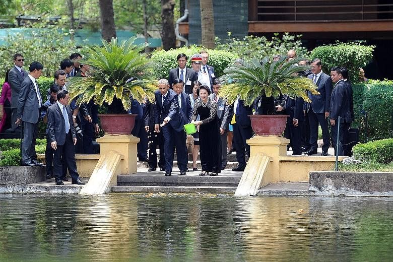 Vietnamese people taking pictures as Mr Obama's motorcade drove past in Hanoi yesterday. The US leader's three-day trip to Vietnam is part of his administration's strategic "rebalance" to Asia. Mr Obama and Ms Nguyen Thi Kim Ngan, chairman of the Vie