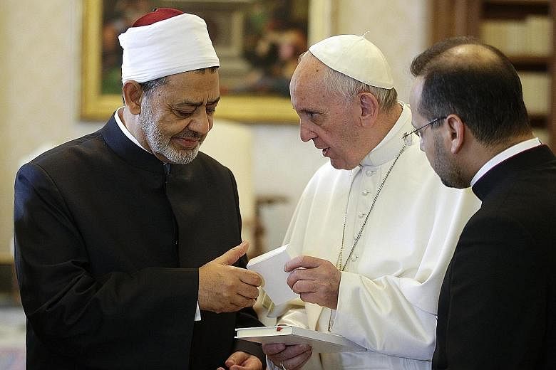 Pope Francis (right) presenting Sheikh Tayeb with a copy of his recent cyclical, Laudato Si', during the Sunni Muslim leader's visit to the Vatican yesterday. Al-Azhar Mosque said the grand imam had accepted the Pope's invitation in order to explore 